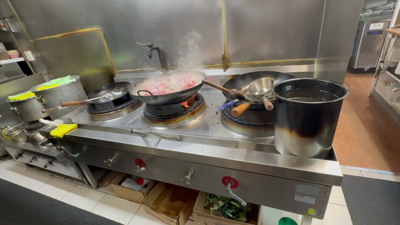 Pho Heaven kitchen with active wok, steam, and flame — where every Sizzling Black Bean Plate starts